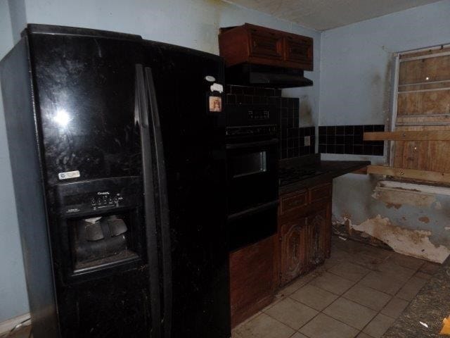 kitchen featuring range hood, dark countertops, black appliances, and light tile patterned floors