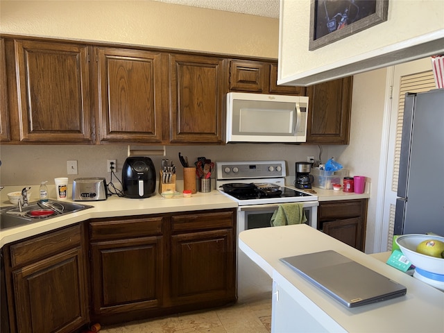 kitchen featuring light countertops, white appliances, and a sink