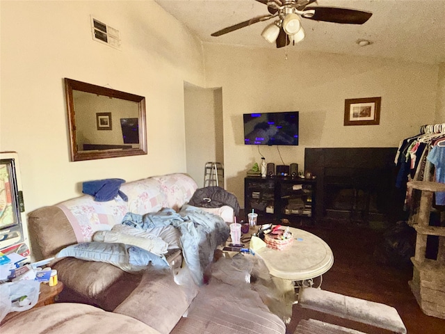 living area featuring lofted ceiling, ceiling fan, and visible vents