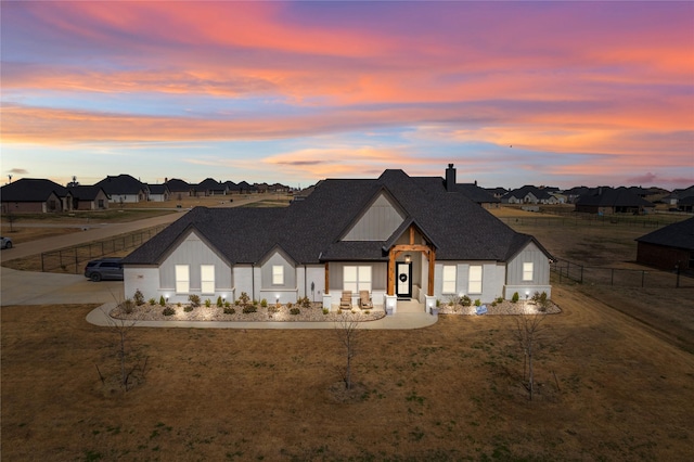 modern farmhouse style home with a shingled roof, a residential view, fence, and board and batten siding