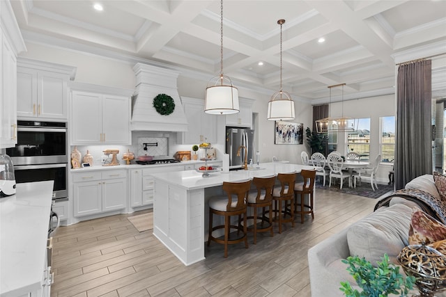 kitchen with wood finish floors, light countertops, appliances with stainless steel finishes, custom exhaust hood, and beam ceiling