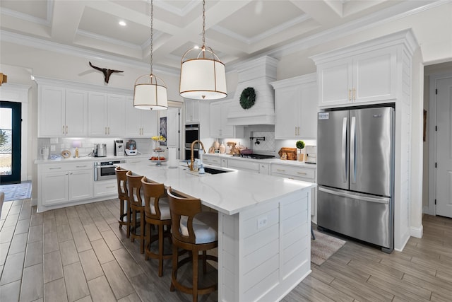 kitchen featuring appliances with stainless steel finishes, an island with sink, a sink, and decorative backsplash