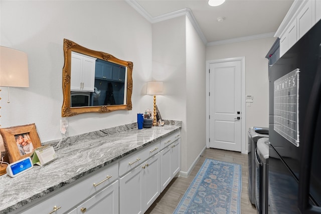 kitchen featuring white cabinets, ornamental molding, light wood-type flooring, independent washer and dryer, and freestanding refrigerator