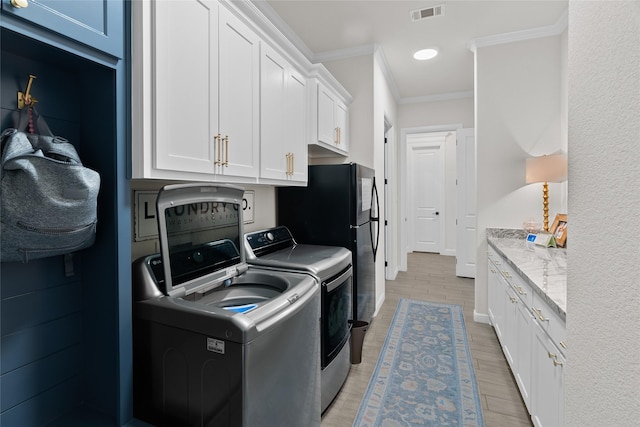 washroom featuring cabinet space, visible vents, washer and clothes dryer, light wood-style flooring, and crown molding