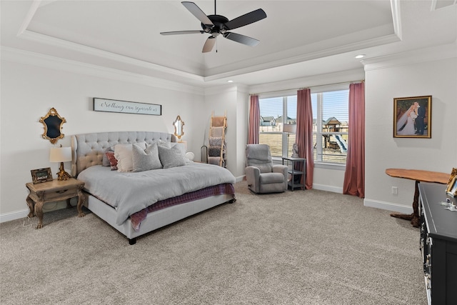 bedroom with baseboards, crown molding, a tray ceiling, and carpet flooring