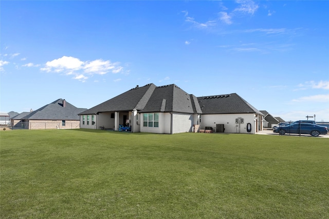 rear view of property featuring a lawn and central air condition unit