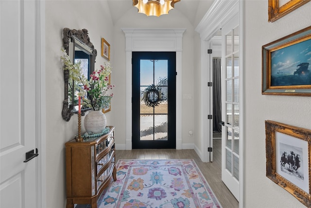 entrance foyer with a wealth of natural light, a notable chandelier, light wood-style flooring, and baseboards