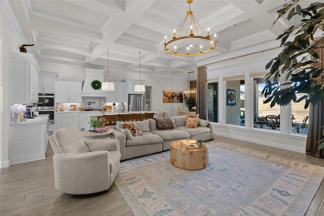 living room with beam ceiling, coffered ceiling, a notable chandelier, and light wood finished floors