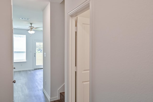 hall with baseboards, visible vents, and wood finished floors