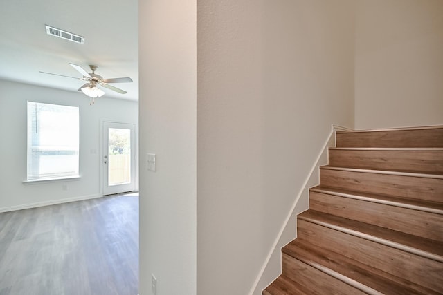 staircase with baseboards, ceiling fan, visible vents, and wood finished floors