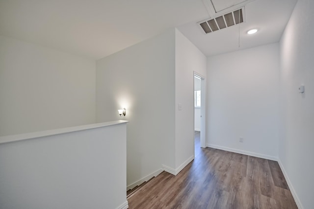 empty room featuring baseboards, attic access, visible vents, and wood finished floors