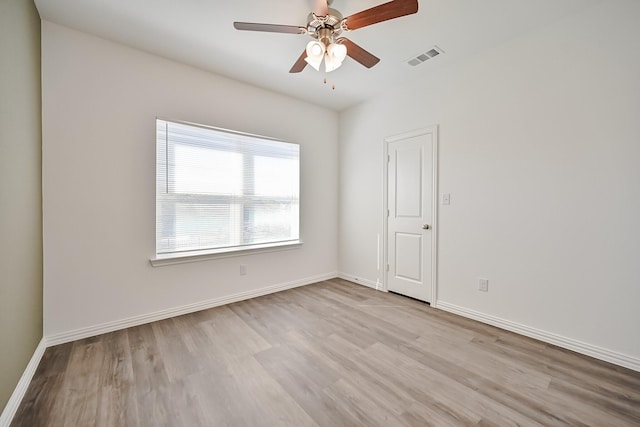 empty room with ceiling fan, wood finished floors, visible vents, and baseboards