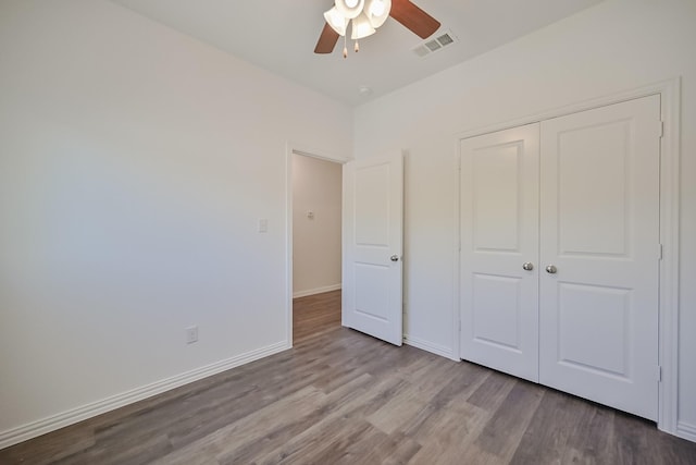 unfurnished bedroom featuring wood finished floors, a ceiling fan, visible vents, baseboards, and a closet