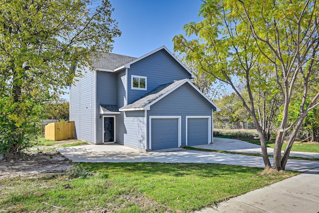 exterior space with roof with shingles, a lawn, fence, a garage, and driveway