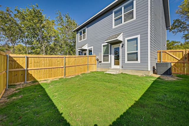 rear view of house with entry steps, a lawn, a fenced backyard, and central air condition unit