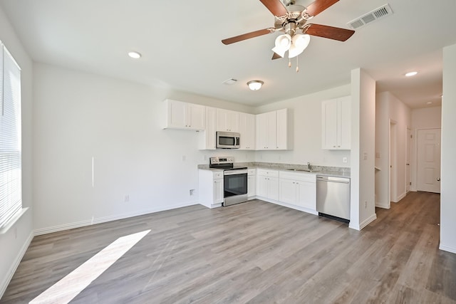 kitchen featuring light wood finished floors, visible vents, appliances with stainless steel finishes, white cabinetry, and a sink