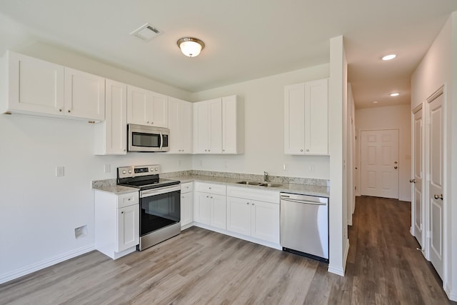 kitchen featuring appliances with stainless steel finishes, white cabinets, visible vents, and a sink