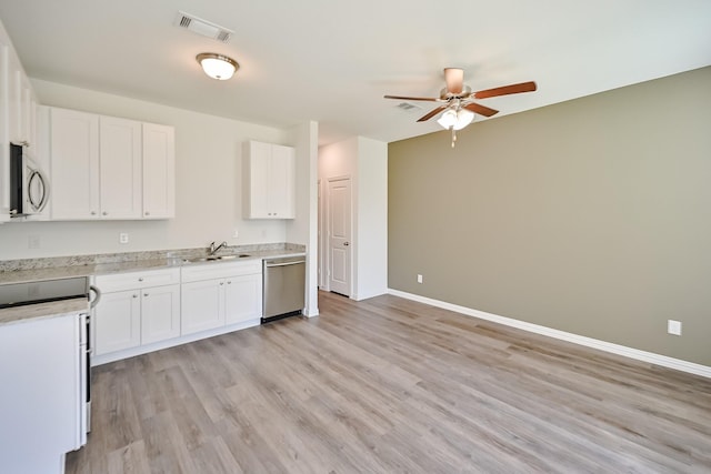 kitchen with visible vents, appliances with stainless steel finishes, white cabinets, a sink, and baseboards