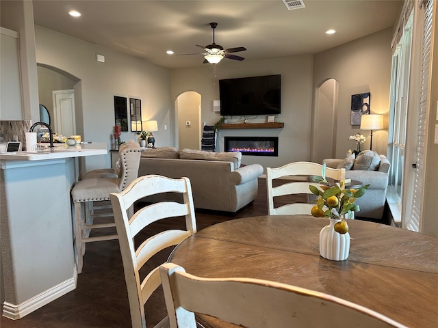 213 Stuart St, Paradise, TX 76073 - dining space with arched walkways, a glass covered fireplace, recessed lighting, ceiling fan, and dark wood-type flooring