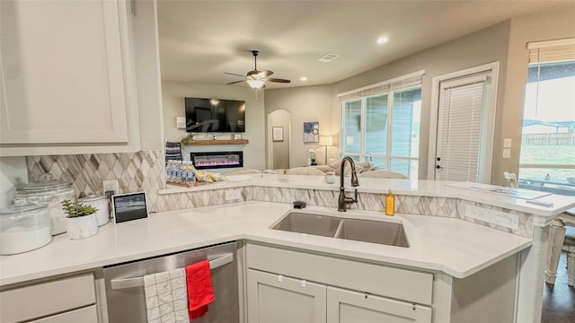 213 Stuart St, Paradise, TX 76073 - kitchen with stainless steel dishwasher, open floor plan, a glass covered fireplace, decorative backsplash, and a peninsula