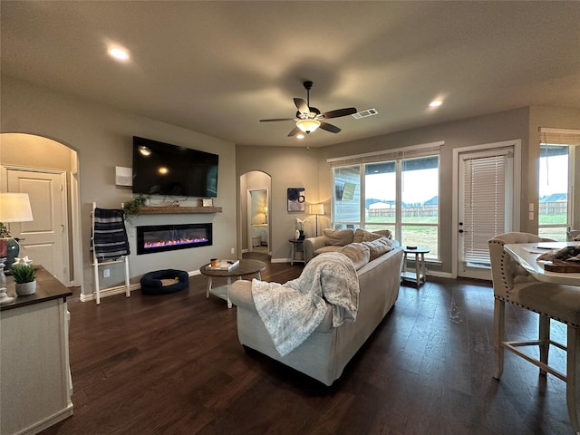 213 Stuart St, Paradise, TX 76073 - living room with arched walkways, dark wood-style flooring, ceiling fan, a glass covered fireplace, and recessed lighting