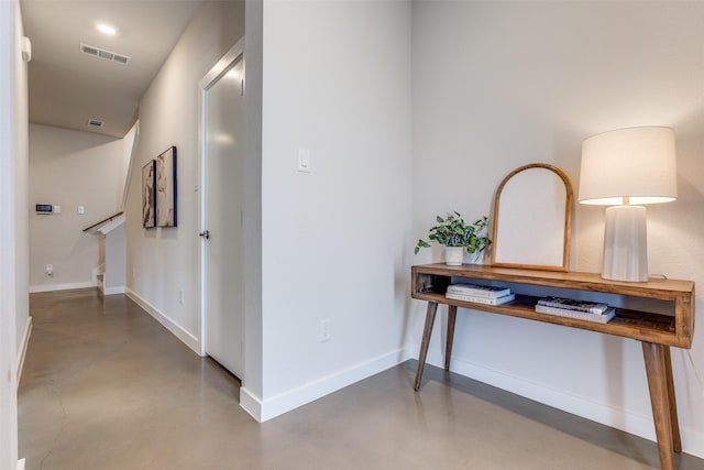 hallway with concrete flooring, visible vents, and baseboards