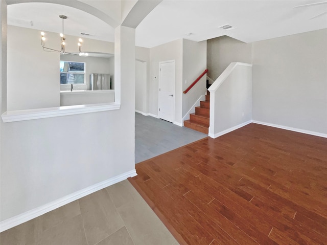 foyer entrance with stairs, visible vents, a chandelier, and wood finished floors