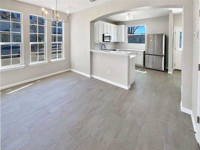 kitchen with arched walkways, appliances with stainless steel finishes, baseboards, and white cabinets