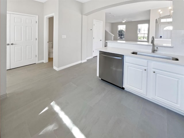 kitchen with arched walkways, light countertops, white cabinets, a sink, and dishwasher