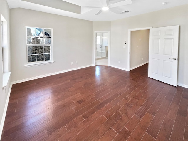 empty room featuring dark wood-style flooring, visible vents, ceiling fan, and baseboards