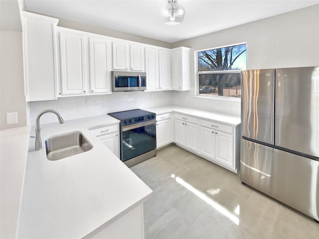 kitchen featuring tasteful backsplash, light countertops, appliances with stainless steel finishes, white cabinets, and a sink