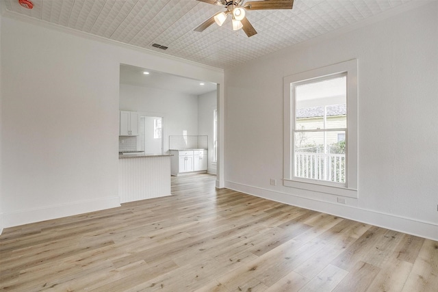 unfurnished living room featuring light wood finished floors, visible vents, baseboards, a ceiling fan, and crown molding