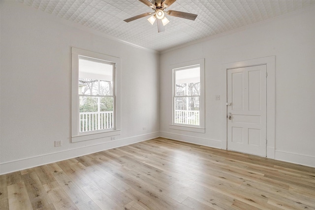 spare room with plenty of natural light, light wood-style flooring, and crown molding