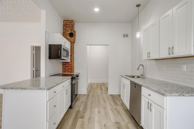 kitchen with visible vents, appliances with stainless steel finishes, light wood-style floors, a sink, and a peninsula