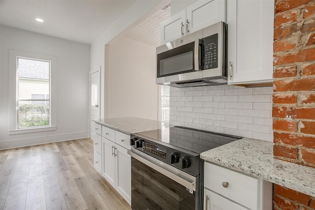 kitchen with electric stove, stainless steel microwave, decorative backsplash, and light stone countertops