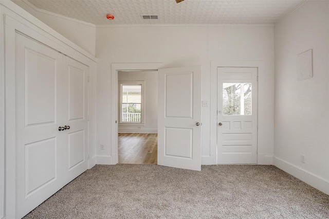 unfurnished bedroom featuring ornamental molding, carpet flooring, visible vents, and baseboards