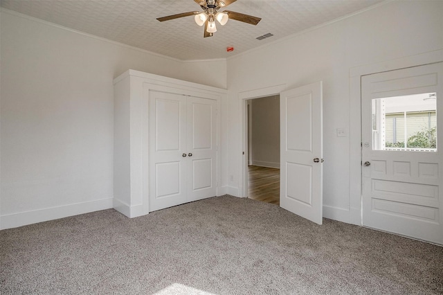 unfurnished bedroom with baseboards, visible vents, crown molding, and carpet flooring