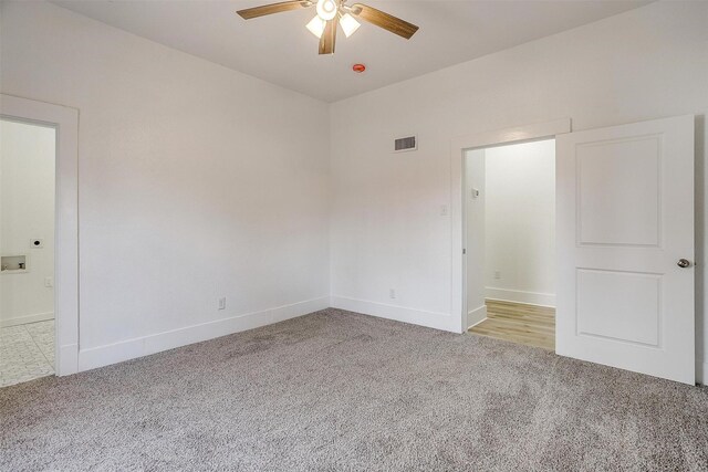 carpeted spare room with ceiling fan, visible vents, and baseboards