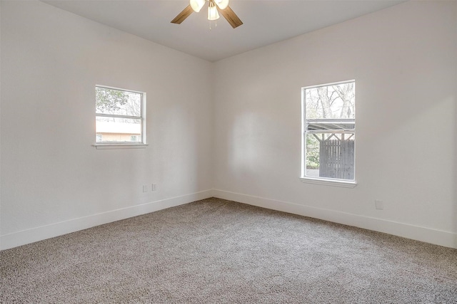 carpeted spare room featuring a ceiling fan and baseboards