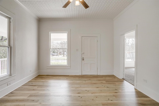 empty room featuring a healthy amount of sunlight, light wood-type flooring, a ceiling fan, and crown molding