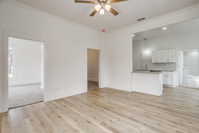 unfurnished living room with ceiling fan, visible vents, baseboards, ornamental molding, and light wood finished floors