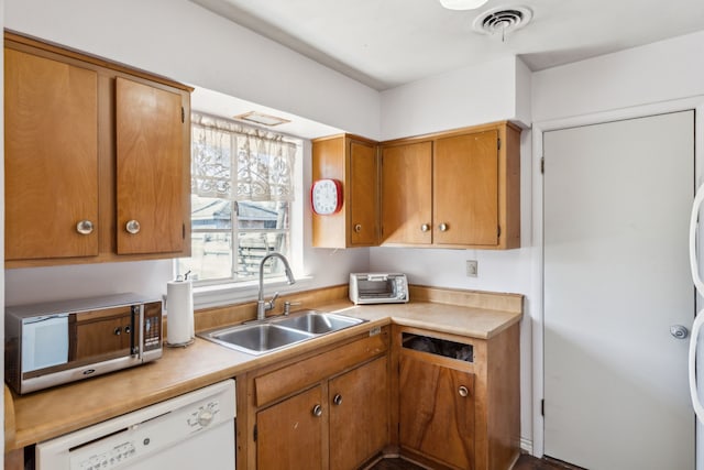 kitchen featuring visible vents, brown cabinetry, white dishwasher, light countertops, and a sink