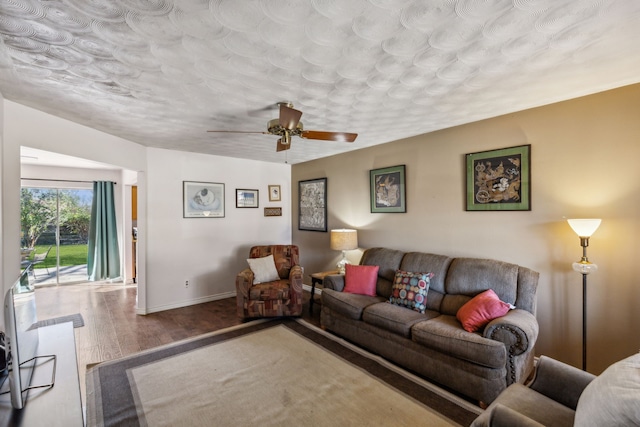 living area featuring wood finished floors, a ceiling fan, and baseboards