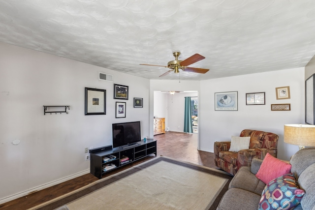 living area featuring visible vents, ceiling fan, baseboards, and wood finished floors