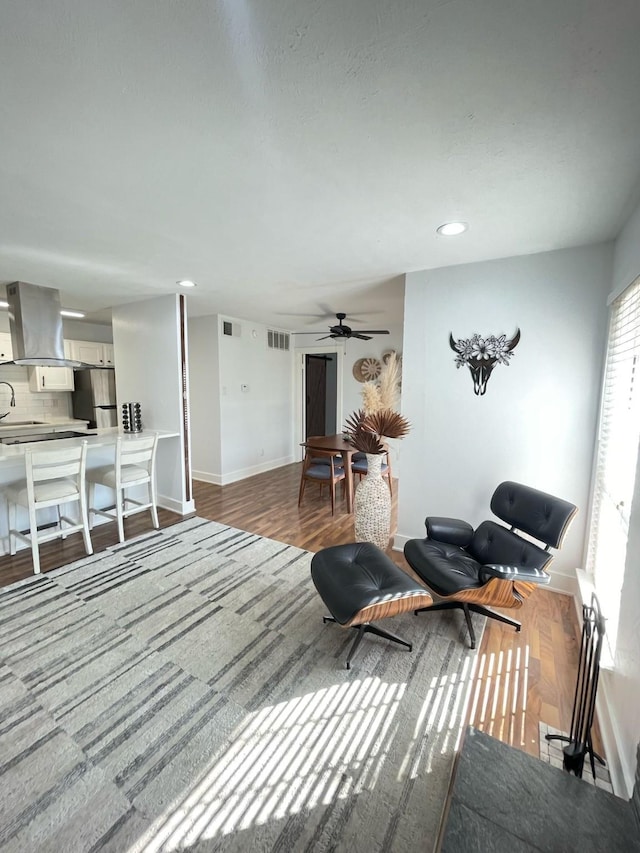 living room with recessed lighting, visible vents, baseboards, and wood finished floors