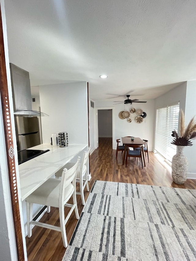 dining space with visible vents, a ceiling fan, a textured ceiling, wood finished floors, and baseboards