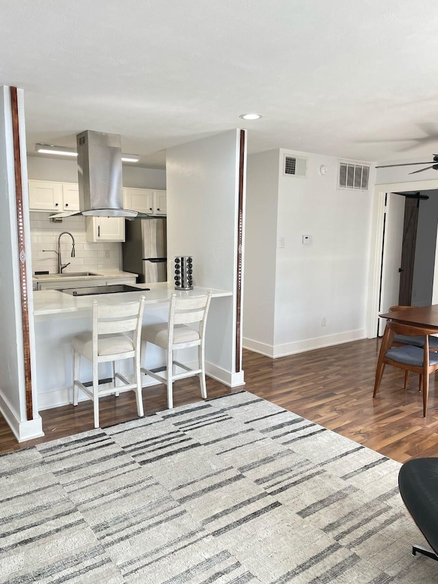 kitchen featuring visible vents, island exhaust hood, freestanding refrigerator, and decorative backsplash