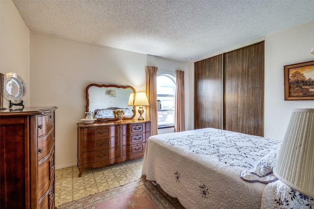 bedroom featuring a textured ceiling, light floors, and a closet