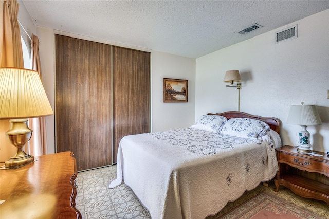 bedroom with a closet, visible vents, and a textured ceiling