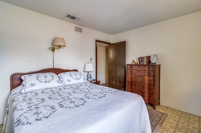 bedroom featuring visible vents, a textured ceiling, and light floors